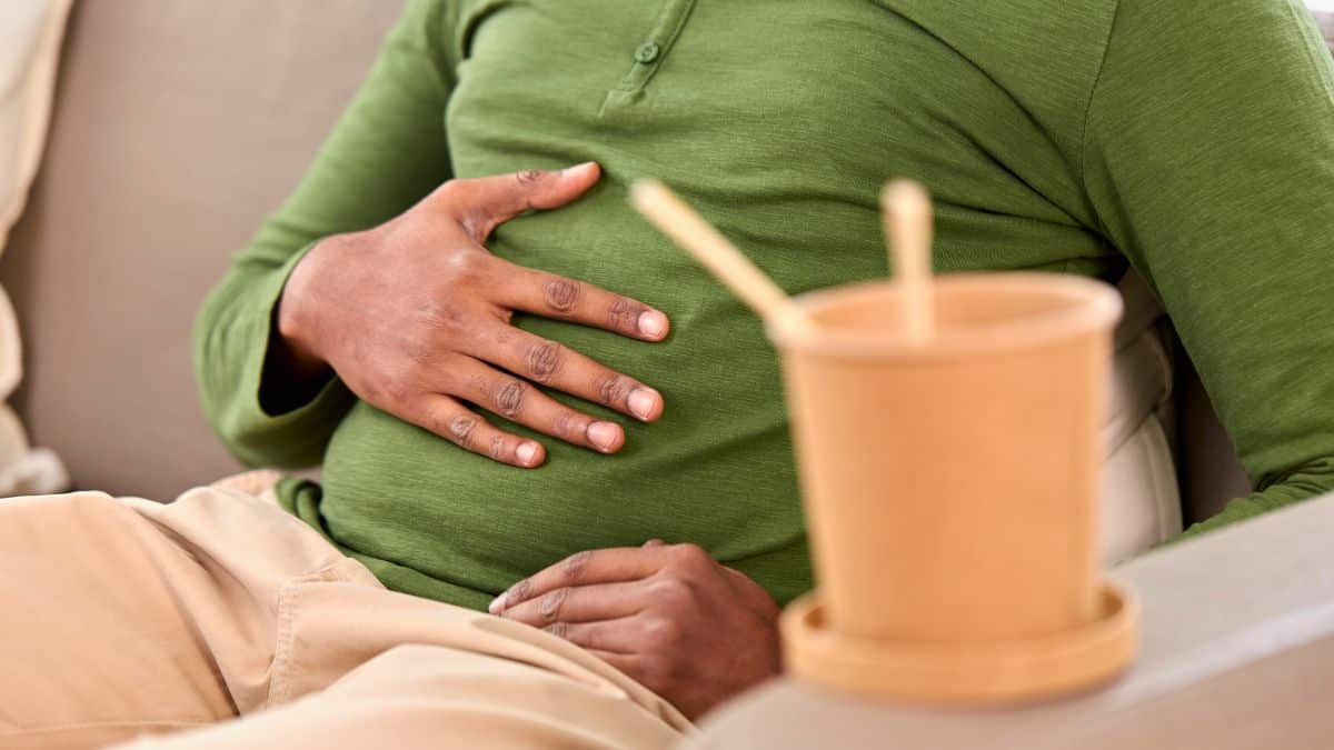 Personne tenant son ventre, tasse en avant-plan.