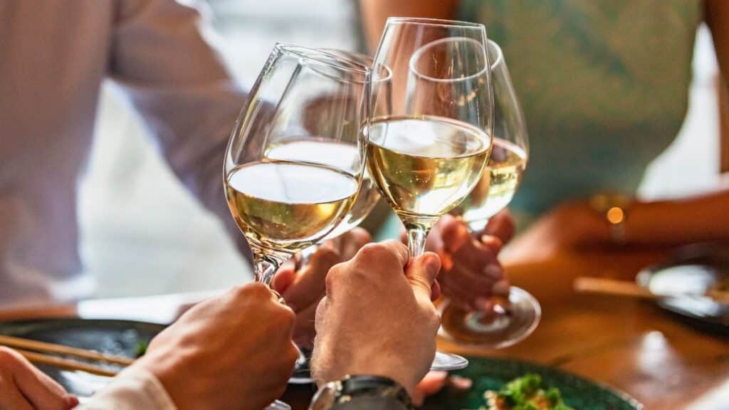 Main levant des verres de vin blanc.