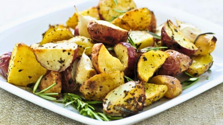 Pommes de terre rôties avec herbes sur assiette blanche.