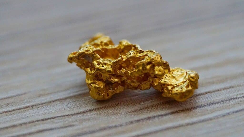 Grosse pépite d'or sur table en bois.