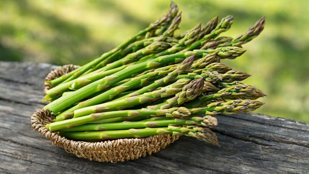 Asperges vertes dans un panier sur bois.