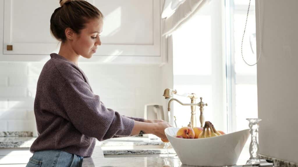 Femme faisant la vaisselle dans une cuisine lumineuse.
