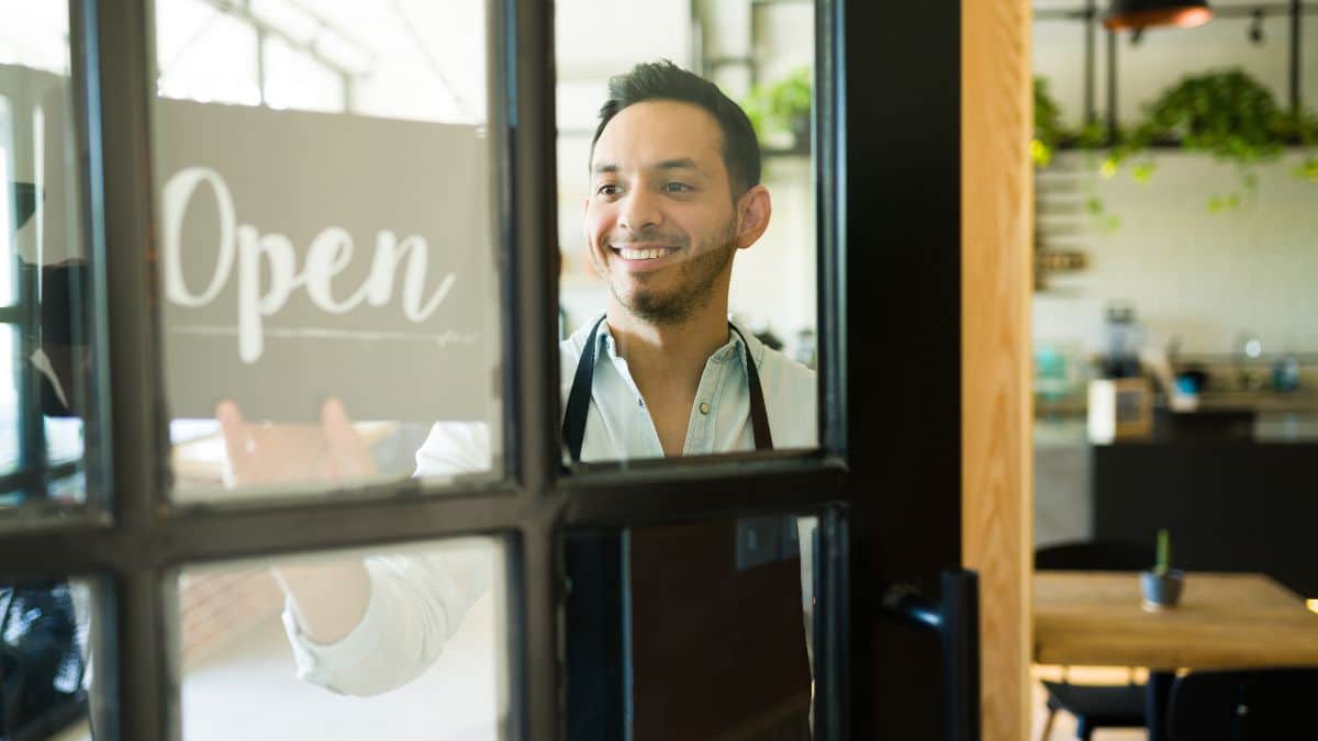 Homme souriant ouvrant sa boutique.
