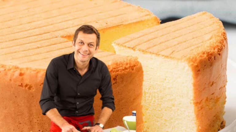 Homme souriant devant un gâteau coupé.