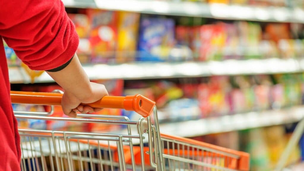Personne poussant un chariot dans un supermarché.