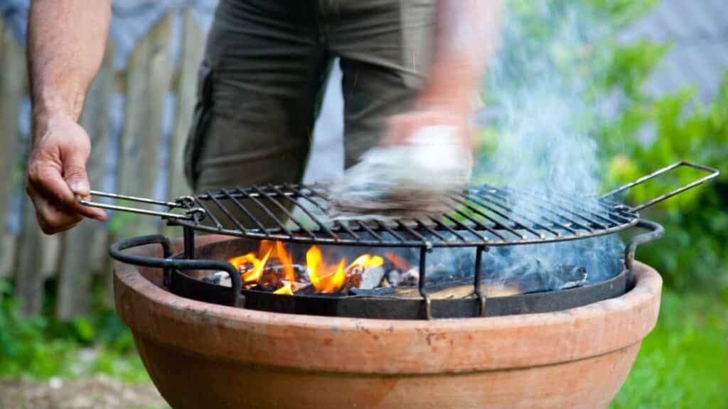 Personne nettoie un barbecue avec des flammes.