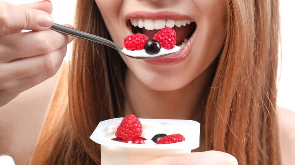 Femme mangeant un yaourt aux fruits rouges.