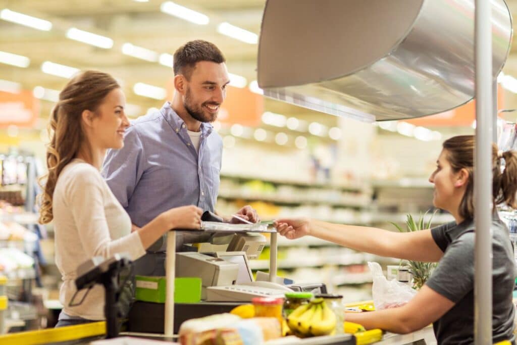 Clients et caissière au supermarché, échange à la caisse.