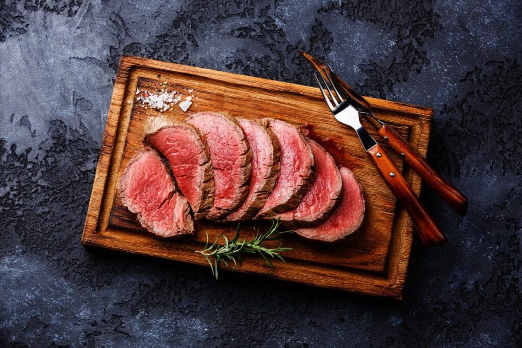 Tranches de bœuf saignant sur planche en bois.
