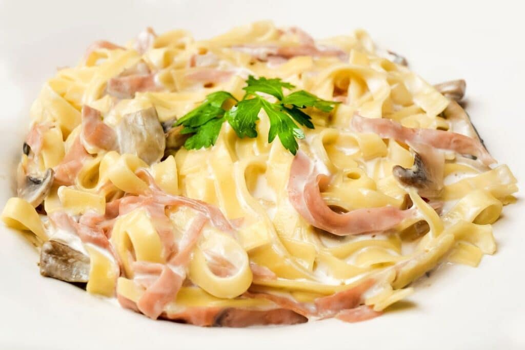 Tagliatelles au jambon, sauce crémeuse et persil.