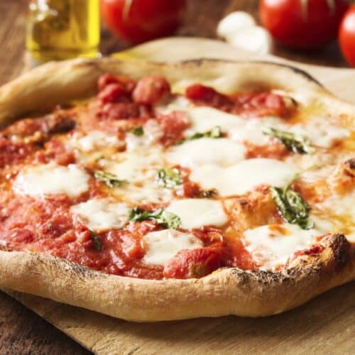 Pizza margherita chaude sur planche en bois.