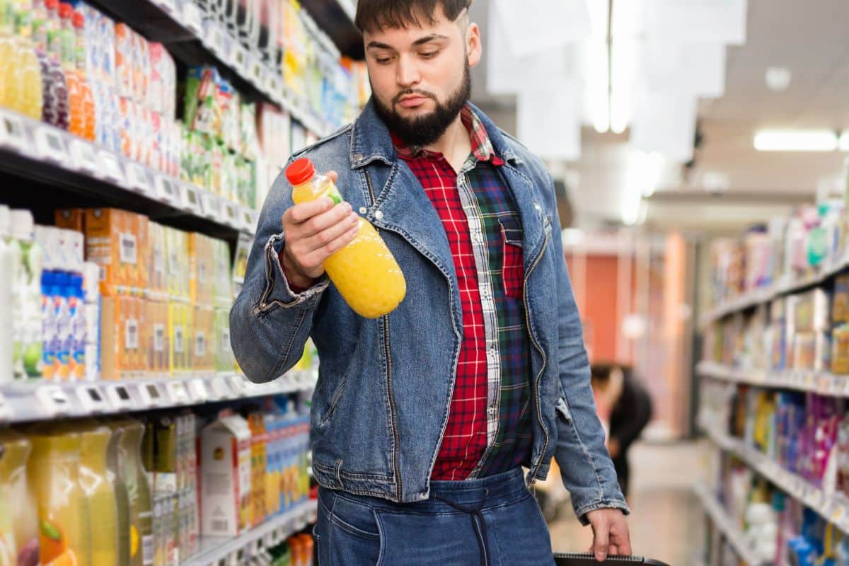 Homme choisissant une boisson au supermarché.
