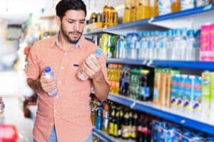 Homme choisissant une bouteille d'eau en magasin.