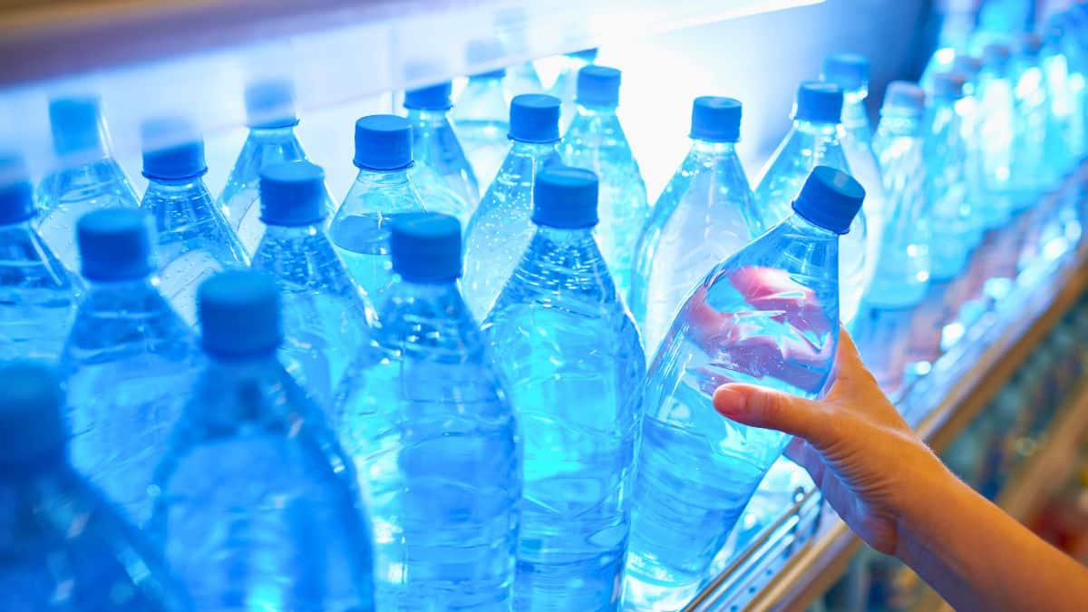 Bouteilles d'eau en rayon, main en prend une.