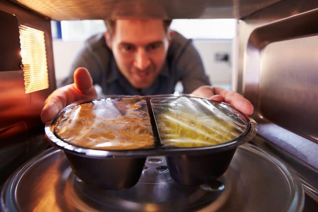 Homme mettant repas préparé au micro-ondes.