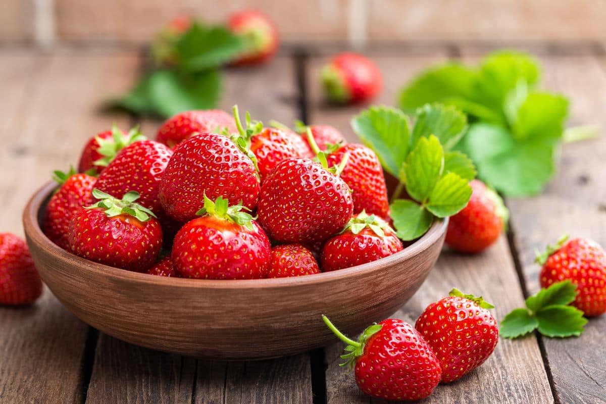 Bol rempli de fraises fraîches sur table en bois.