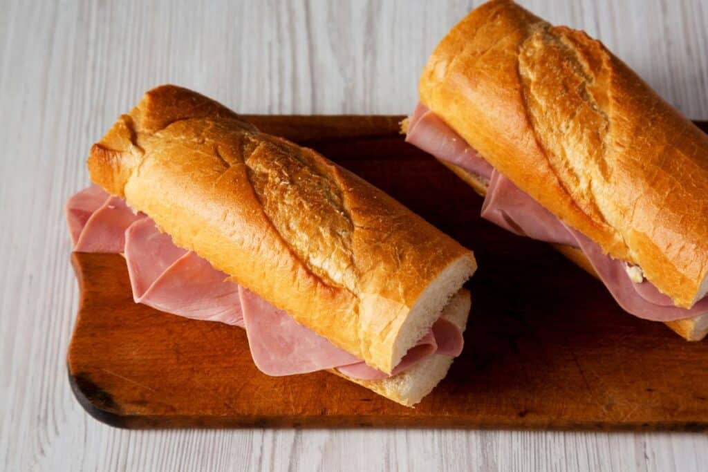 Deux sandwiches jambon sur planche en bois.
