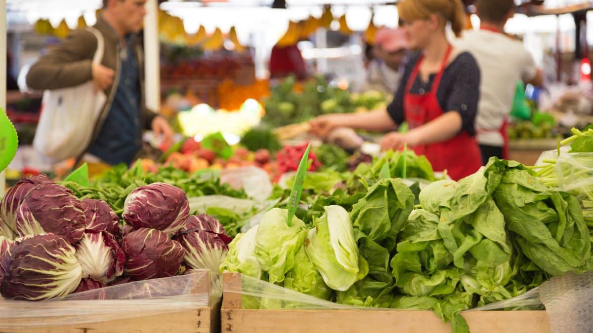 Marché avec légumes frais et vendeurs occupés.