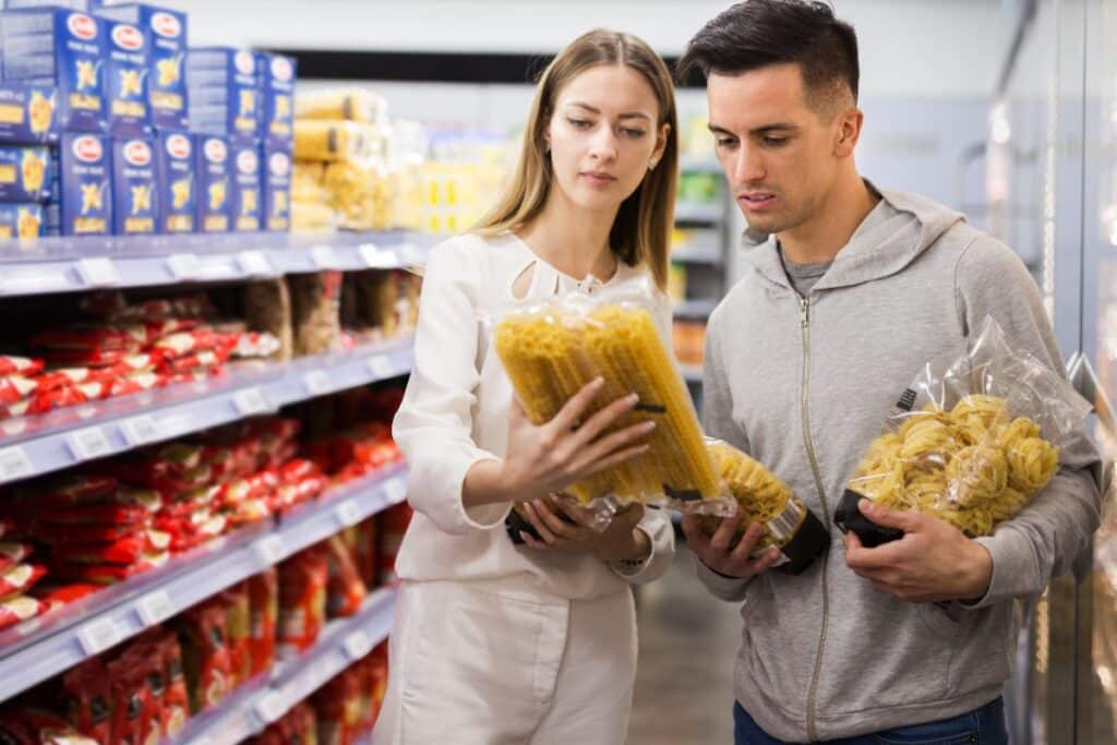 Couple choisissant des pâtes dans un supermarché.