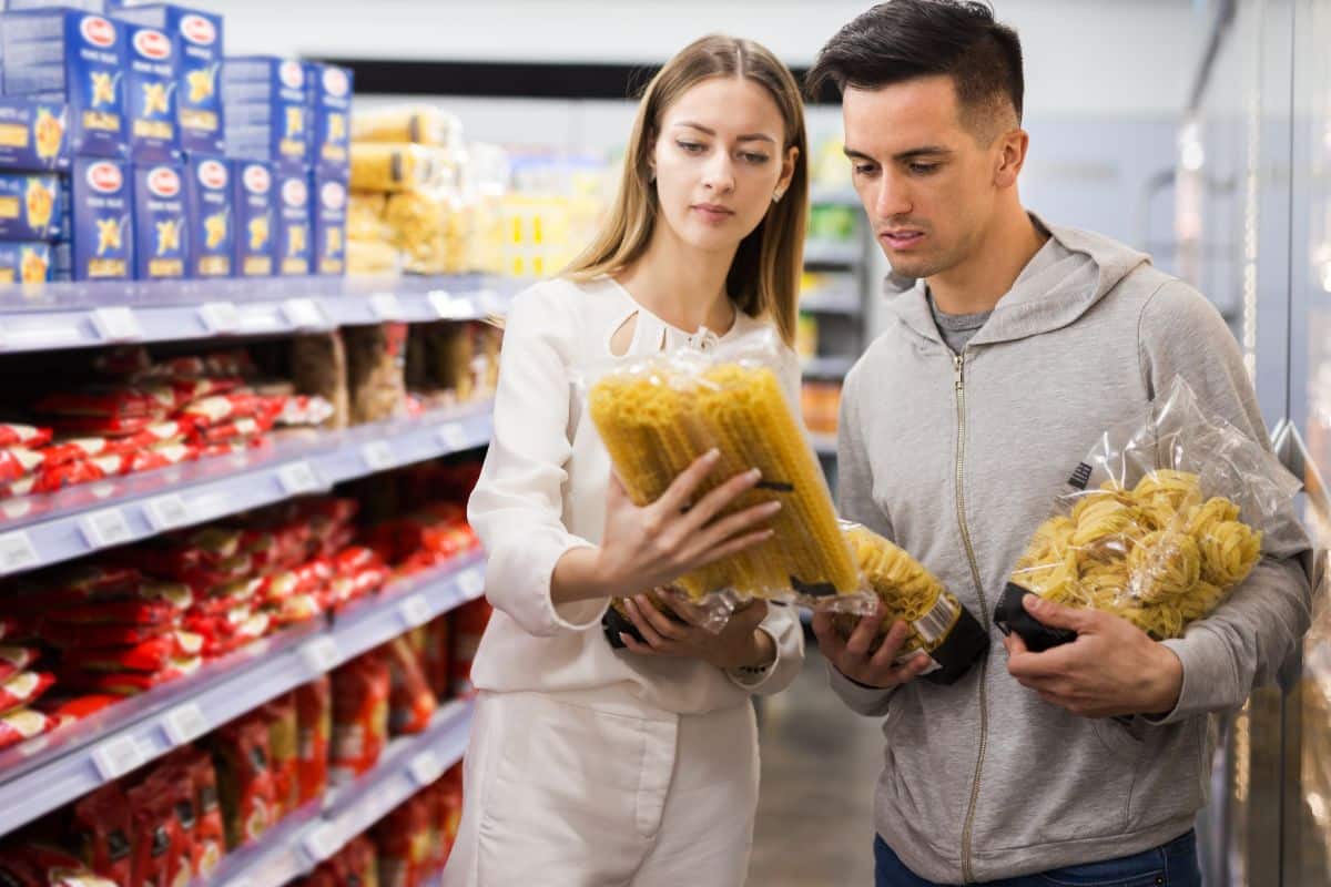 Couple choisissant des pâtes dans un supermarché.