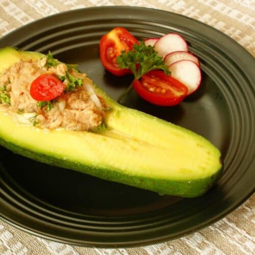Avocat farci au thon, tomates, et radis. Assiette noire.