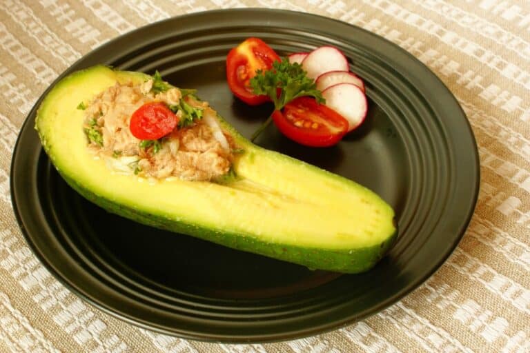 Avocat farci au thon, tomates, et radis. Assiette noire.