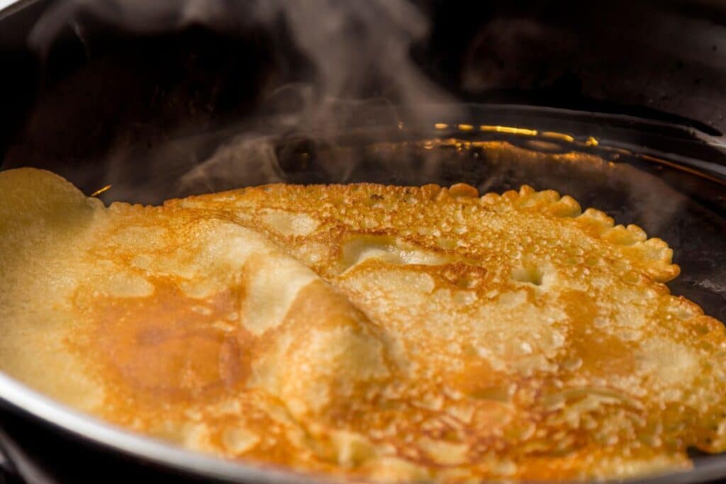 Crêpe chaude dans une poêle, vapeur visible.