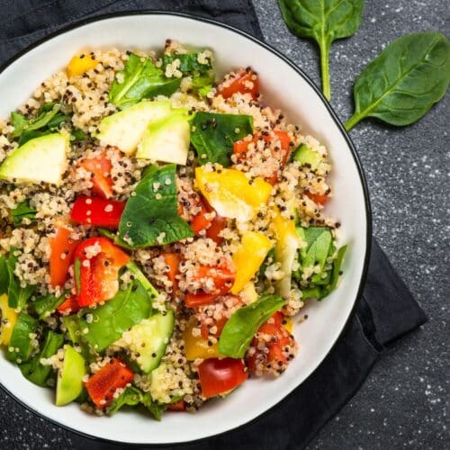 Salade de quinoa avec légumes colorés dans bol blanc.