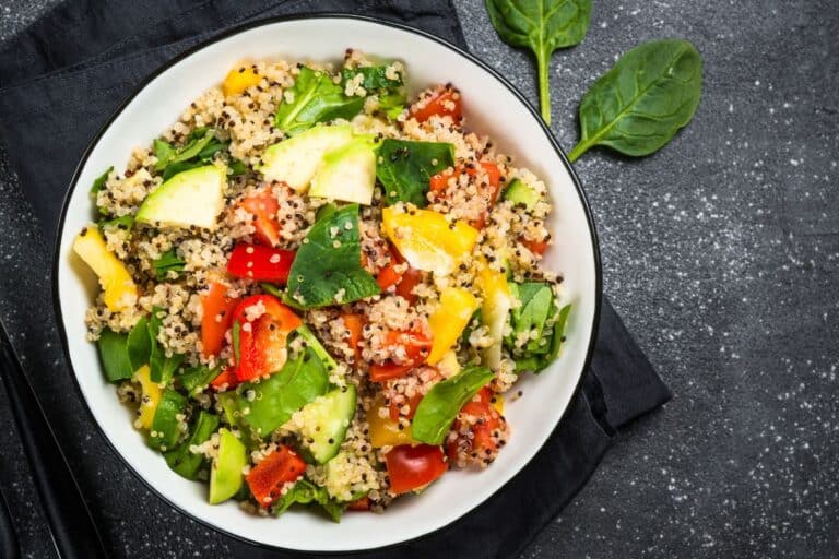 Salade de quinoa avec légumes colorés dans bol blanc.