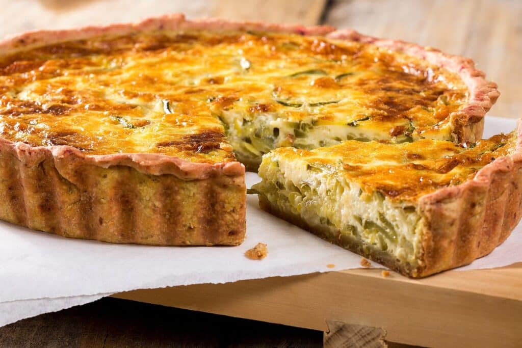 Quiche au fromage et légumes sur planche en bois.