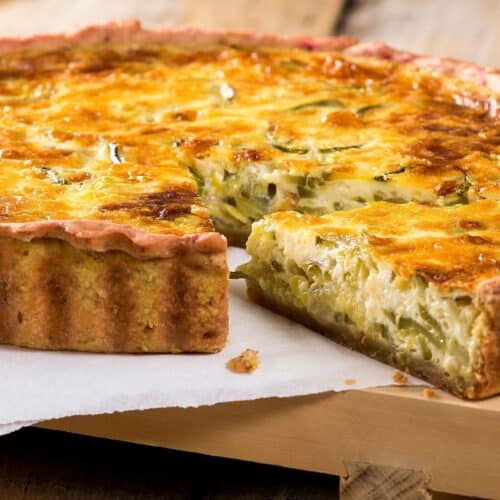 Quiche au fromage et légumes sur planche en bois.