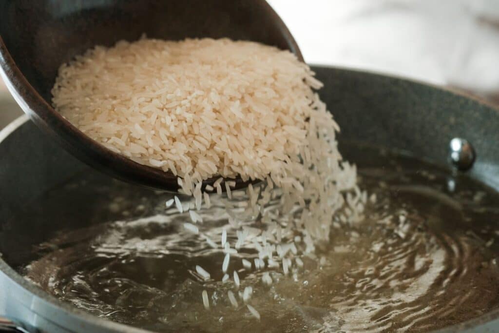 Versement de riz dans une casserole d'eau bouillante