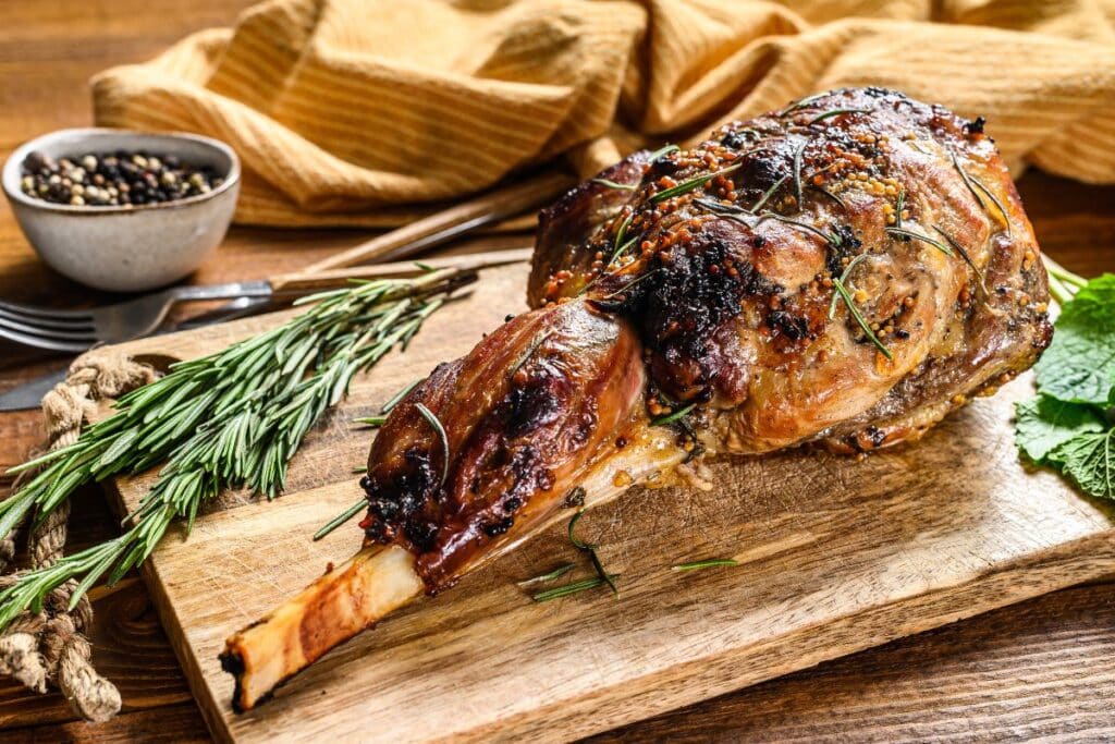 Gigot d'agneau rôti avec herbes sur planche.