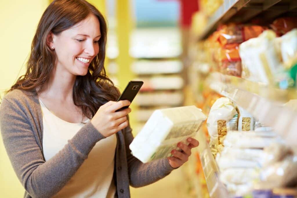 Femme scanne produit avec smartphone en magasin.