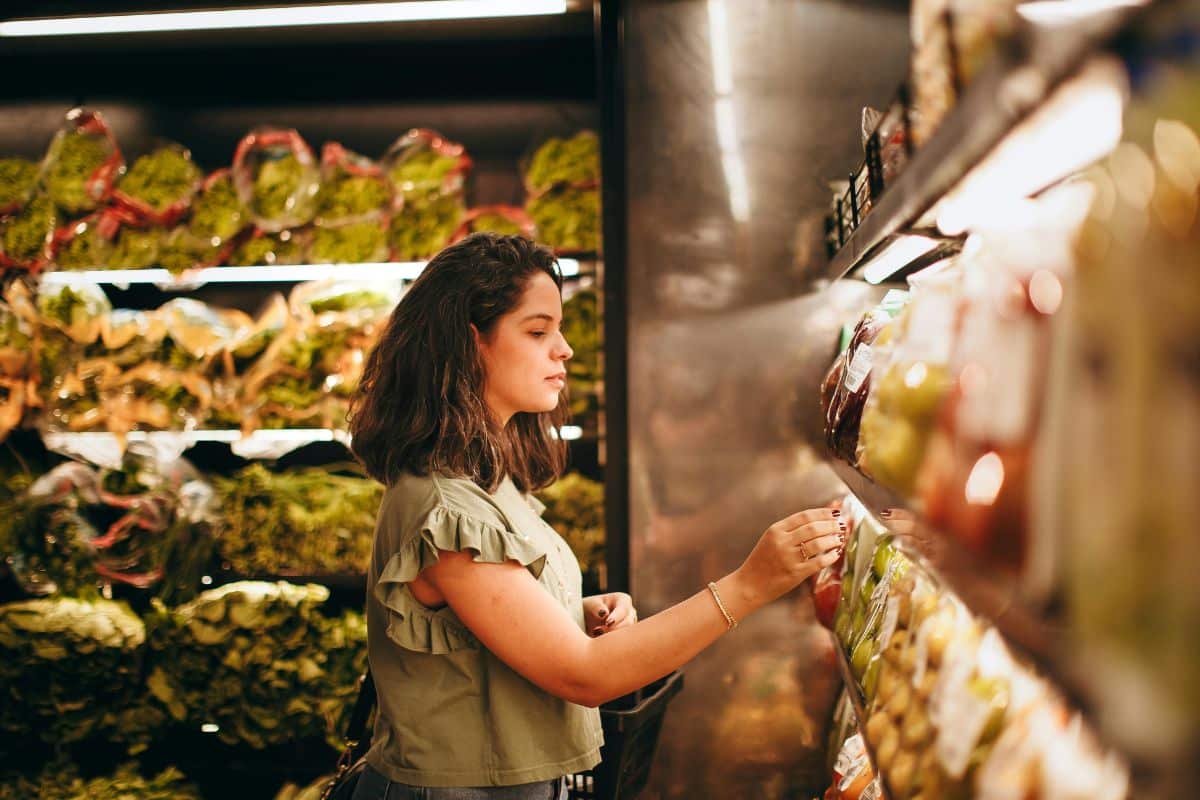 Femme choisissant des légumes au supermarché.