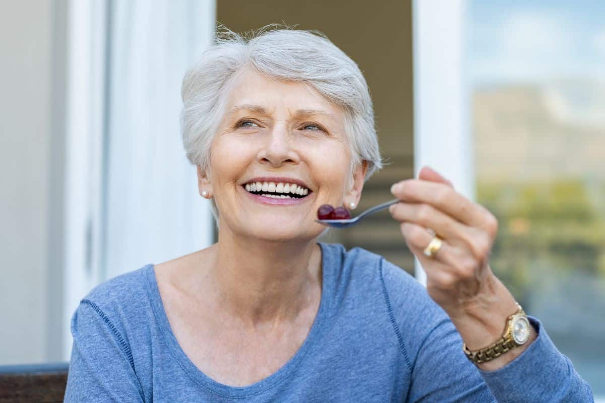 Femme souriante mangeant à l'extérieur.