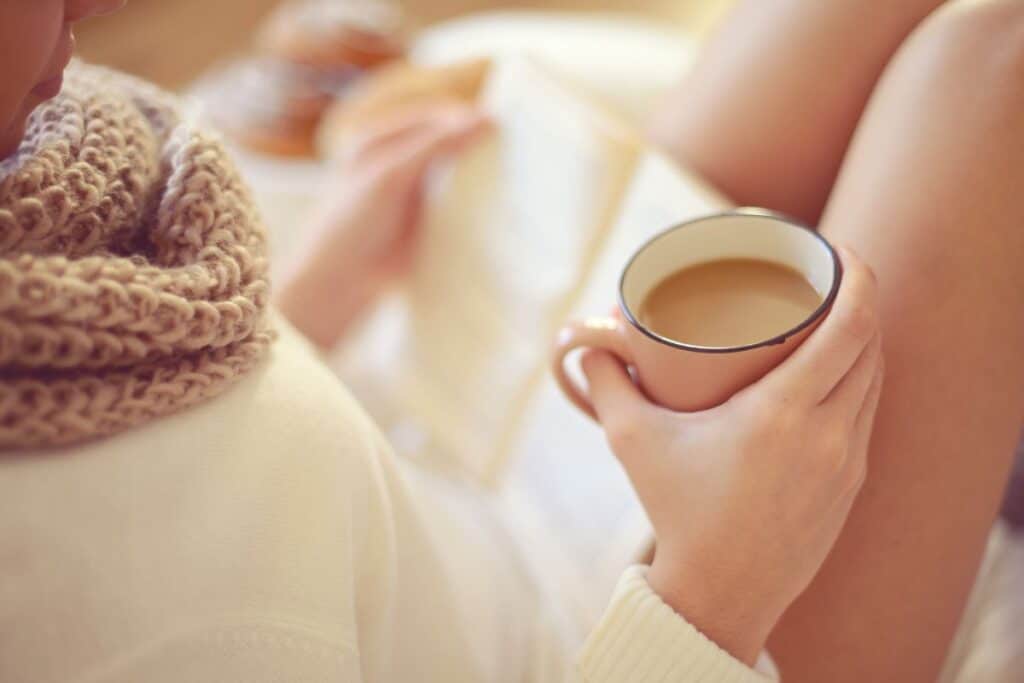 Personne lisant avec café et écharpe.