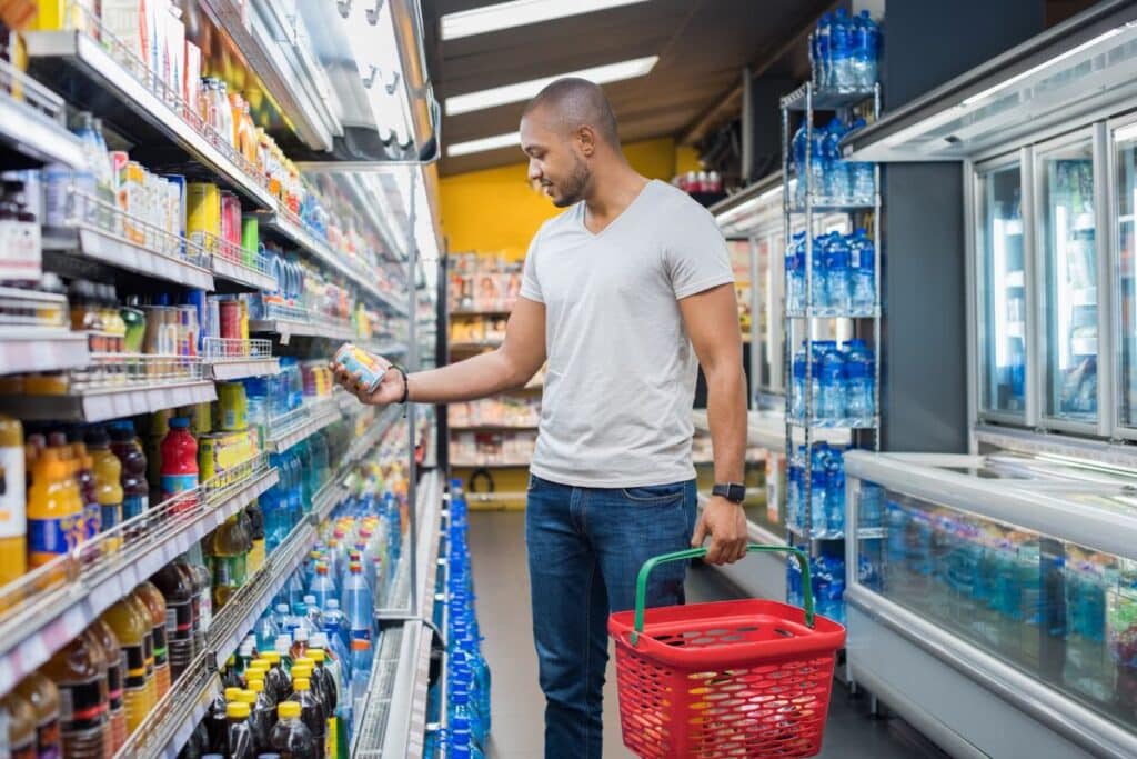 Homme choisissant une boisson dans un supermarché.