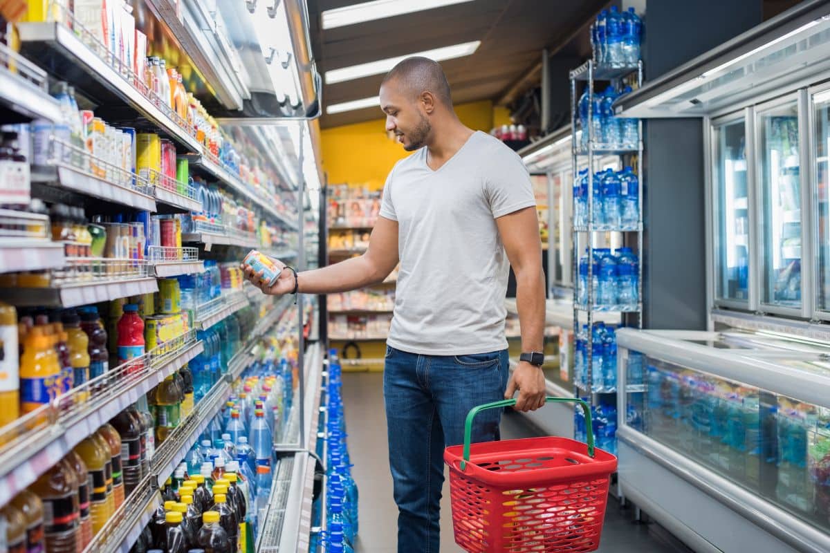 Homme choisissant une boisson dans un supermarché.
