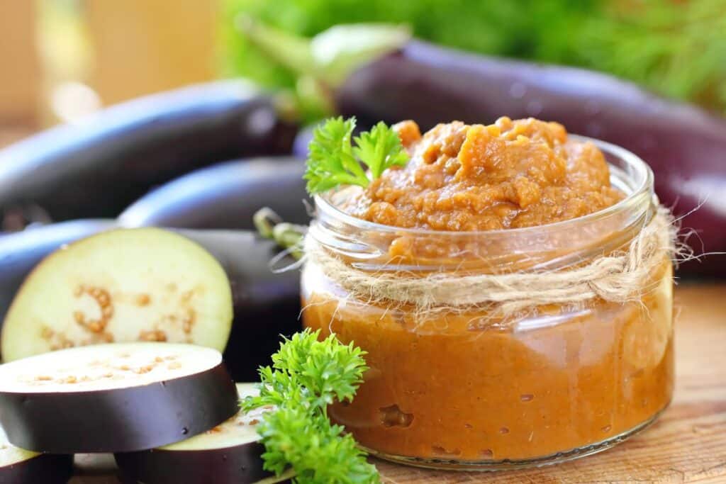 Caviar d'aubergine en bocal avec aubergines fraîches.