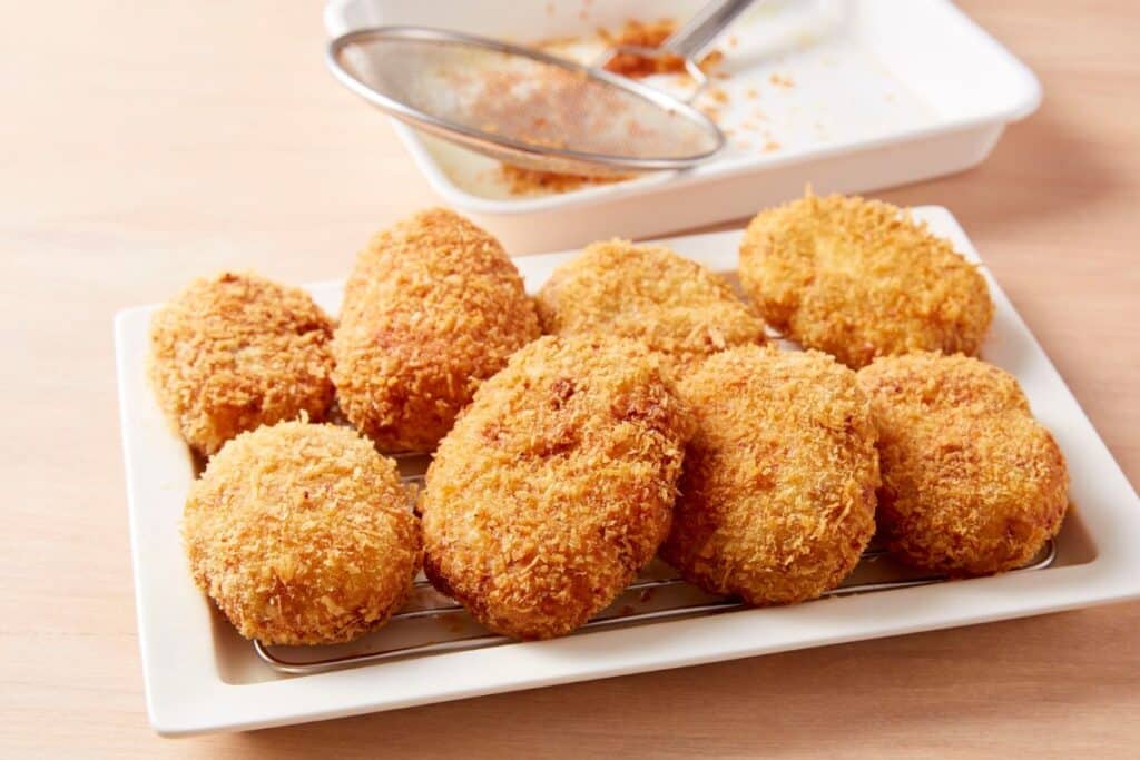 Croquettes dorées et croustillantes sur une assiette blanche.