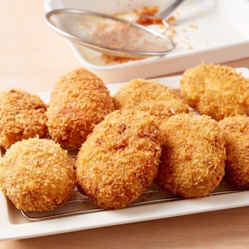 Croquettes dorées et croustillantes sur une assiette blanche.