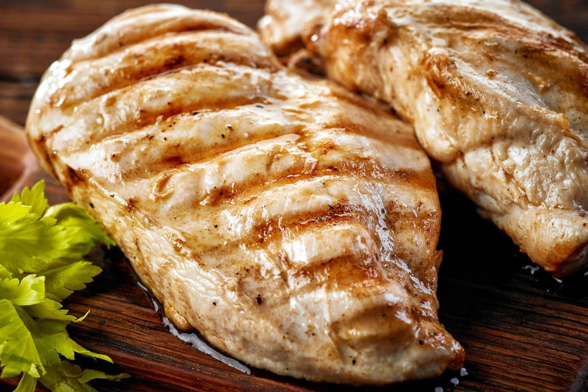 Filets de poulet grillés sur planche en bois.