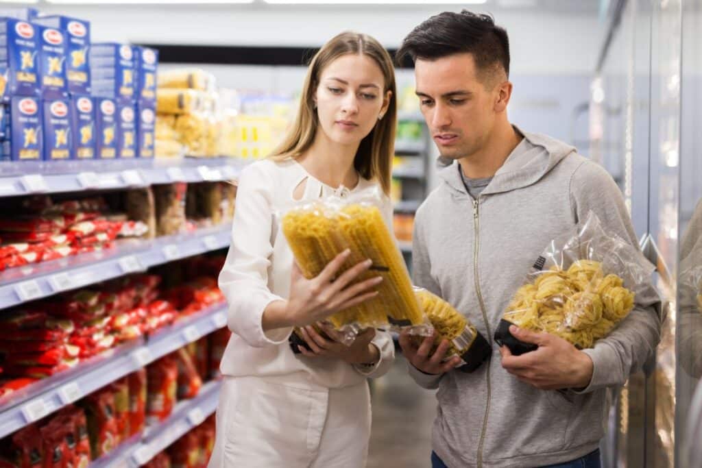 Deux personnes choisissent des pâtes au supermarché.