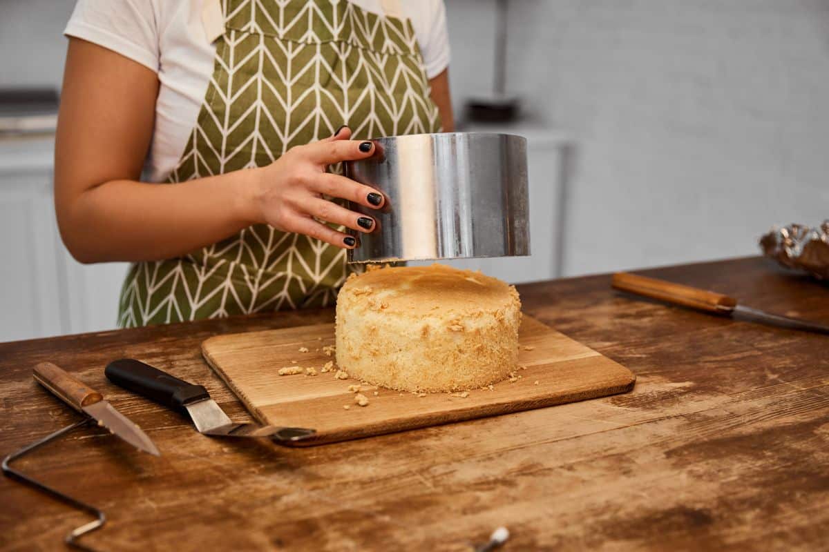 Personne démoulant un gâteau sur planche en bois.