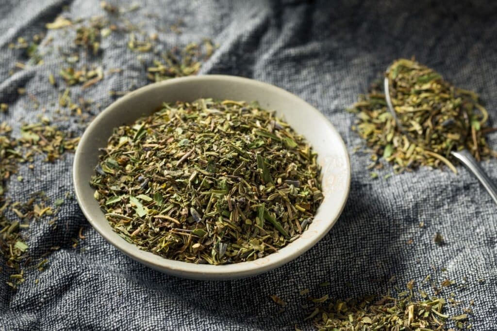 Bol d'herbes de Provence sur tissu gris.
