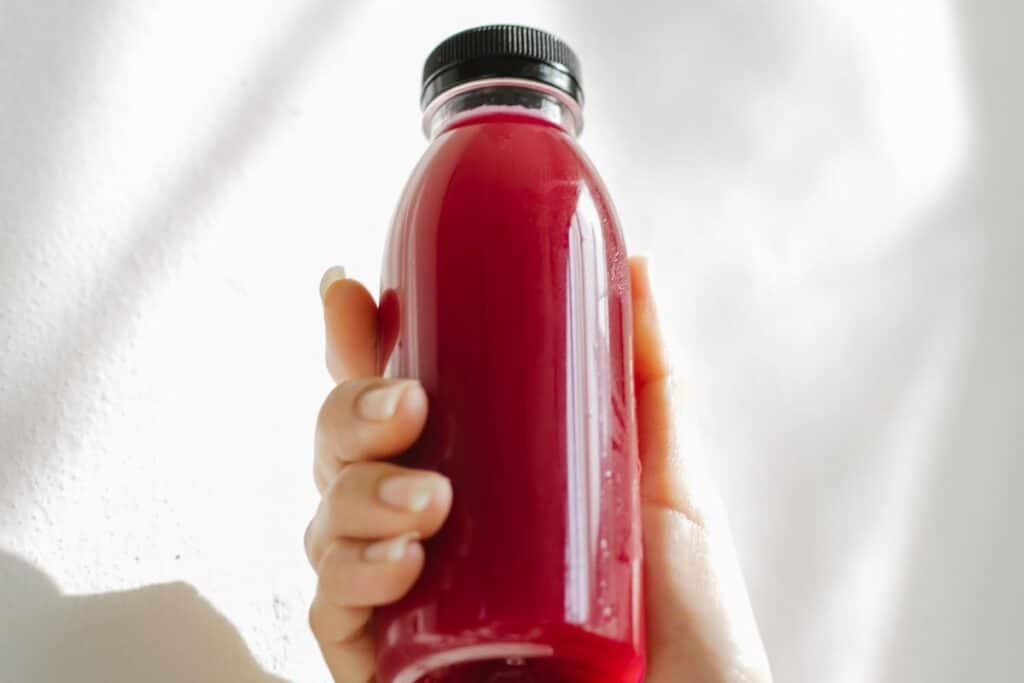 Main tenant une bouteille de jus rouge