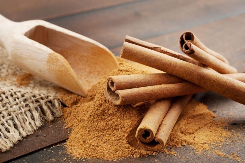 Bâtons et poudre de cannelle sur table en bois.