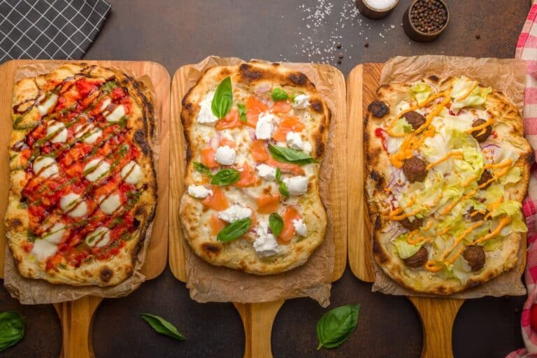 Trois pizzas variées sur planches en bois.