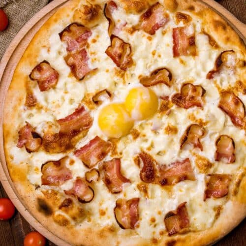Pizza au bacon et œufs sur planche.